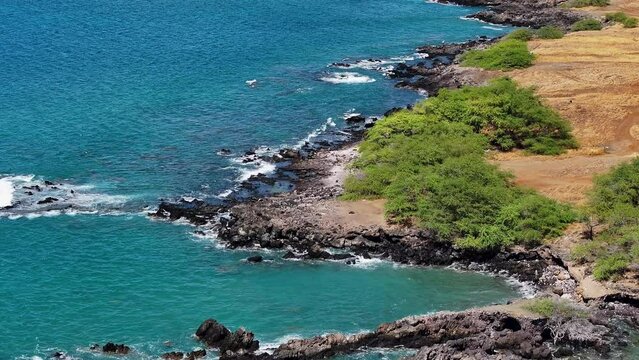Aerial coastal hills rocky beach Kona Hawaii. Big Island, largest, most volcanic active destination. Economy is tourism. Beautiful clear blue ocean sea. Rocky cliff. Waves and surf.