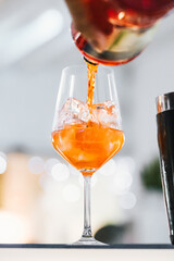 Bartender pouring alcohol from the bottle preparing a spritz. Close-up