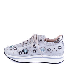 Side view of silver-gray woman's sneaker with a white sole, rivets, pearls, and flower decorative elements isolated on a white background with copy space. Shoe sale. Spring fashion concept.