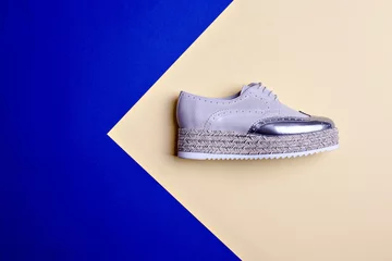  Trendy women's grey-silver platform oxford shoe isolated on two-color background with pointing on copy space. The concept of modern stylish footwear. Creative design for shoe store advertising poster. © Sundaylights