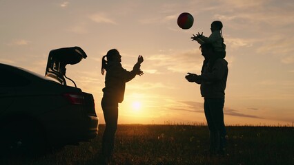 Dad with child, daughter, mother, children play with ball against sunset next to car. Happy family...