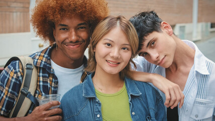 Group of multi-ethnic happy friends, two guys and girl, looking at the camera with smile