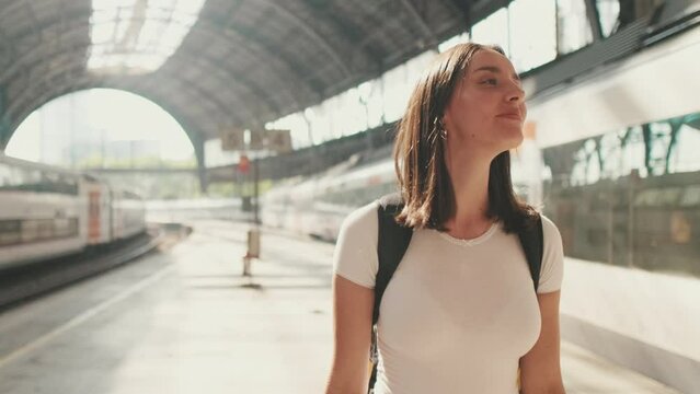 Young woman walk along the platform of the railway station in her hands with mobile phone