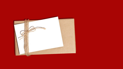 Gift box or present wrapped in craft paper with blank white card. Christmas present. Copy space. Mockup. Flat lay