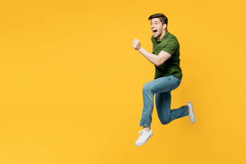 Full body side profile view young sporty cool fun happy man he wearing green t-shirt casual clothes jump high run fast hurry up isolated on plain yellow background studio portrait. Lifestyle concept. - obrazy, fototapety, plakaty
