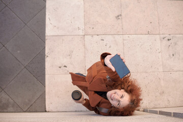 top view of red-haired woman in winter showing cell phone with smile