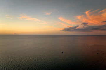 Aerial view of lonesome white yacht at sunset floating on sea waves with ripple surface. Motor boat recreation on ocean surface