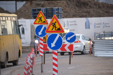 Roadworks warning traffic signs of construction work on city street and slowly moving cars