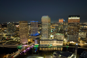 View from above of illuminated skyscraper buildings, pedestrian riverwalk and street traffic in downtown of Tampa city in Florida, USA. American megapolis with business financial district at night