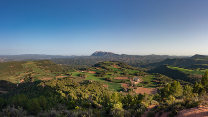 Fototapeta na wymiar Spring in Catalonia. Montserrat over the green fields. A panoramic view from Turó de les Tres Creus @ Catalonia, Spain.