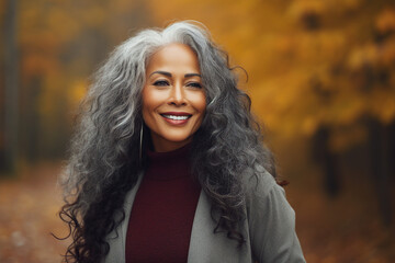 Fototapeta premium Generative AI image of happy beautiful woman walking in the park blurred forest and orange dry leaves background