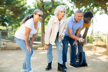 Portrait of friendly mature couples playing petanque at leisure