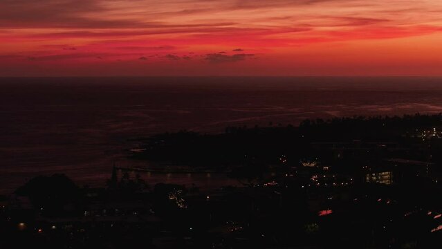 Aerial Kona Hawaii city dark red sunset cityscape. Big Island. Luxury exclusive resorts  homes on coast with tropical landscape. Economy is tourism based. Water and tropical beach recreation and fun.