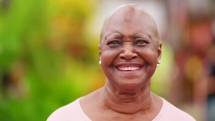 Close-up face of a happy black older bold woman. Portrait of a confident African American senior with no hair smiling at camera