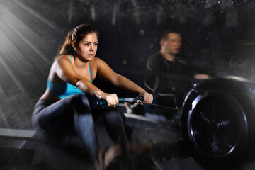 Fototapeta na wymiar Active young woman training at cable row machine in gym