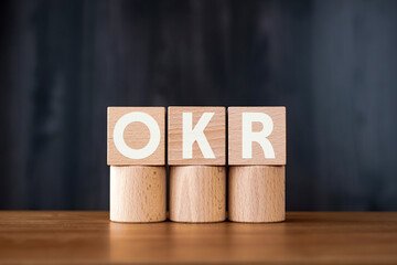 There is wood cube with the word OKR. It is an abbreviation for Objectives Key Results as eye-catching image.