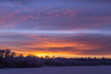 Idyllic sunset with a colorful cirrus clouds above a frozen river.