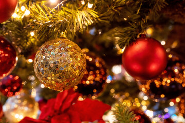 Obraz na płótnie Canvas Christmas balls on fir tree and highlights. Gold tree ornament. Christmas and New years eve Background.