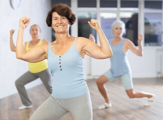Three elderly women are learning sports Latin American dances in studio class. Joint pastime,...