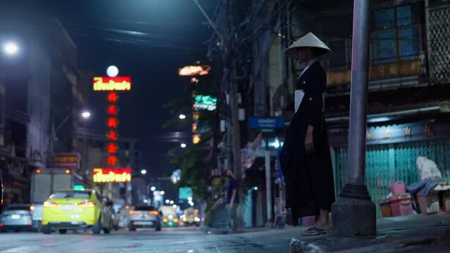 Woman With Conical Hat Stands Amidst Busy Road