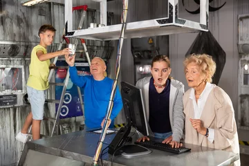 Foto op Plexiglas Young boy and girl resolving riddles with their grandfather and grandmother in escape room. © JackF