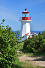 Fototapeta na wymiar Forillon National Park red and white small lighthouse at the end of a hiking trail. Gaspé Cape area.