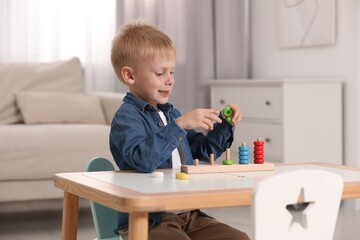 Cute little boy playing with stacking and counting game at table indoors. Child's toy