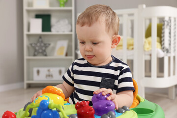 Portrait of cute baby with toy walker at home. Learning to walk