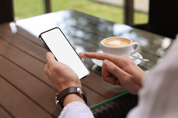 Man using mobile phone at table in outdoor cafe, closeup