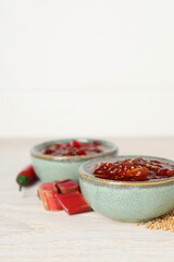Tasty rhubarb sauce and ingredients on white wooden table, closeup. Space for text