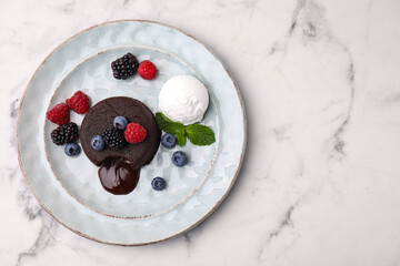 Delicious chocolate fondant served with fresh berries and ice cream on white marble table, top...