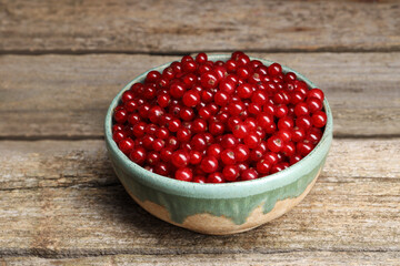 Ripe red currants in bowl on wooden table, closeup