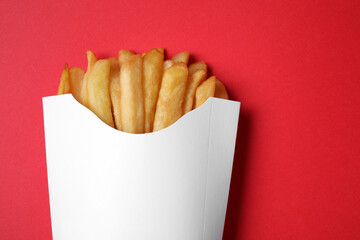 Paper cup with French fries on red table, top view. Space for text - Powered by Adobe
