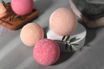 Beautiful aromatic bath bombs and green twig on grey table
