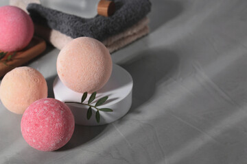 Beautiful aromatic bath bombs and green twig on grey table, space for text
