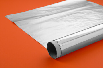 Roll of aluminum foil on orange background, closeup - obrazy, fototapety, plakaty