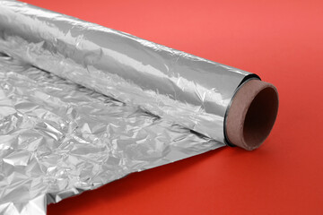 Roll of aluminum foil on orange background, closeup