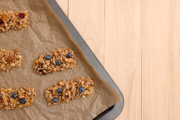 Baking tray with different granola bars on wooden table, flat lay and space for text. Healthy snack