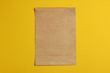 Sheet of old parchment paper on yellow background, top view