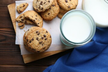 Delicious chocolate chip cookies and milk on wooden table, flat lay