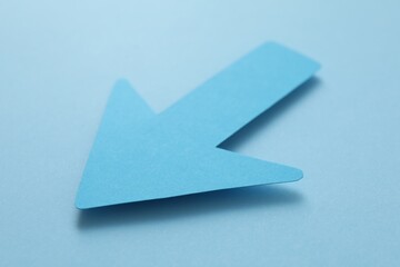 One paper arrow on light blue background, closeup