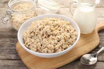 Tasty boiled oatmeal served on wooden table, closeup