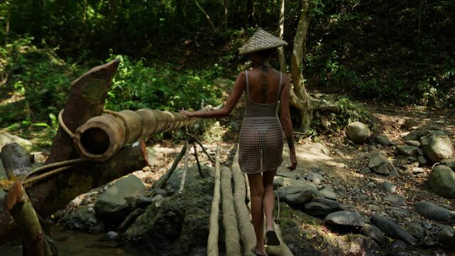 Woman Crossing A Small Bamboo Bridge