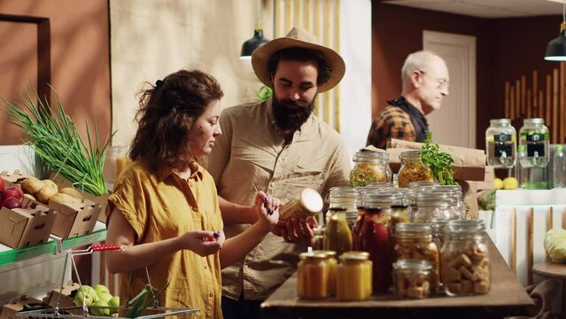 Portrait of happy couple in zero waste supermarket using shopping basket to purchase bulk items in nonpolluting glass containers. Smiling clients in local grocery shop buying organic pantry staples