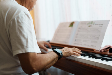 An older man is playing the piano in a living room. He is a musician.