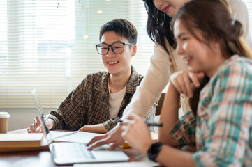 A happy and smart young Asian man in eyeglasses is in the meeting with his team.