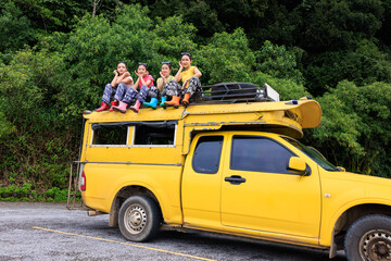 teenager girl friends group sitting on the roof of yellow a minibus, chiamg mai thailand, amazing travel tourist in the rain season concept,