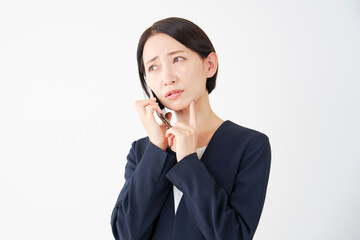 スマートフォンで電話しながら考えるビジネスウーマン　白背景
