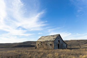 Rural landscape of a rustic, weathered and abandoned barn alone in the emptiness of the vast prairies.