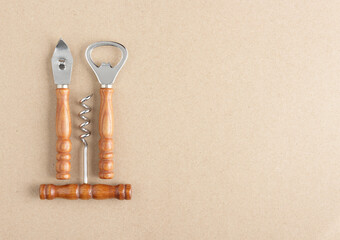 bar set (bottle opener, wine opener, can opener) on brown paper background with copy space